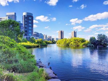 Scenic view of river by buildings against sky