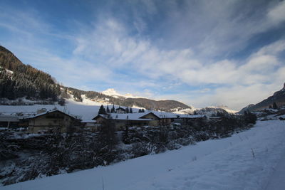 Houses on snow covered landscape against sky