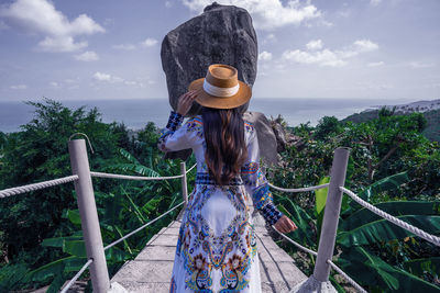 Rear view of woman wearing hat standing against sky