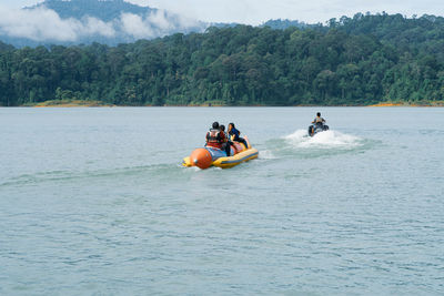 Rear view of people sitting on boat in lake