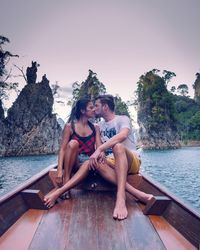 Couple kissing while sitting in boat on sea