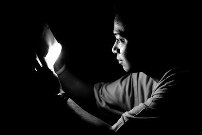 Close-up of man holding lit candle in darkroom