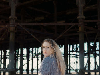 Portrait of young woman standing against built structure