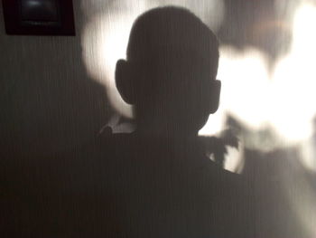 Close-up portrait of woman with shadow on wall at home