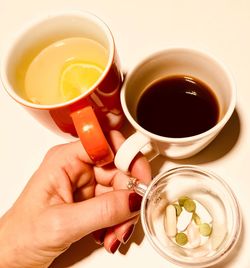 Cropped hand of woman holding food and drink in mug