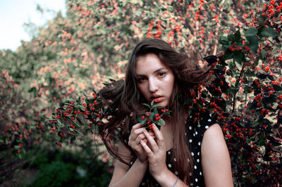 Portrait of beautiful woman standing by berry plant
