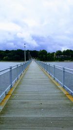 Empty road leading to bridge against sky