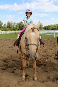 Happy girl riding horse at ranch