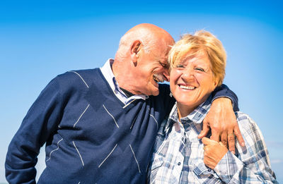 Senior couple kissing against blue sky