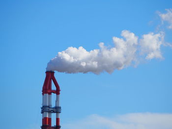 Low angle view of smoke emitting from chimney against sky