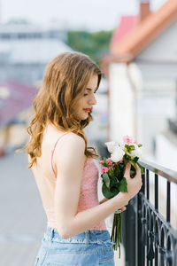 A beautiful young girl in light clothes holds a bouquet of roses in her hands person