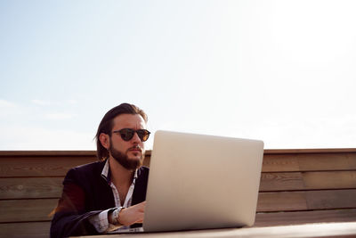 Young woman using laptop while sitting on table against white background