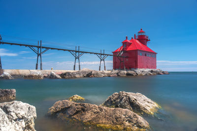 Lighthouse by sea against buildings