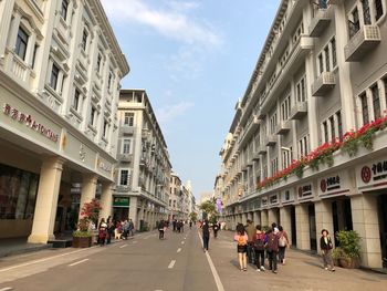 People walking on street in city against sky