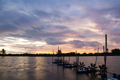 Silhouette boats in sea against sky during sunset