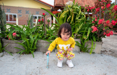 Portrait of smiling girl holding flower plant in yard