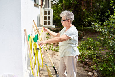 Senior women in her garden with gardening tools, women with eye glasses, sunny day