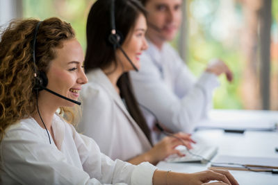 Side view of female customer representatives talking over headsets in office