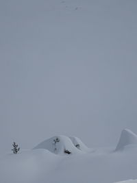 Snow covered landscape against clear sky