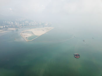 High angle view of cityscape by sea against sky