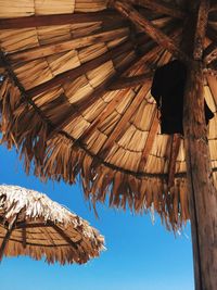 Low angle view of thatched roofs against clear blue sky