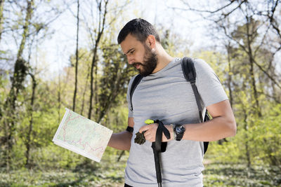 Hiker holding map while standing in forest