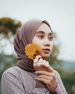 Portrait of woman holding red flower