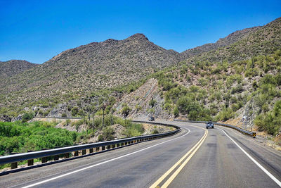 Road by mountain against blue sky