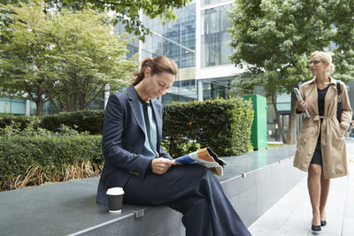 Businesswoman reading paper with colleague leaving after work at city