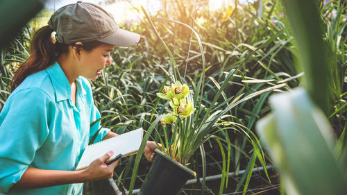 Female researcher examining flowers in greenhouse