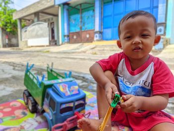 Portrait of cute boy playing with toys on street