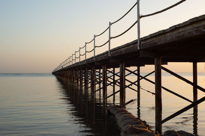 Pier over sea against sky during sunset