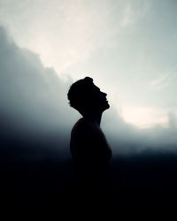 Silhouette man standing on rock against sky during sunset