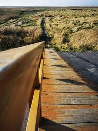 Boardwalk leading towards landscape against sky