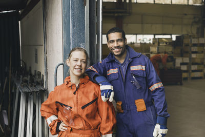 Confident male and female blue-collar workers in protective workwear at factory