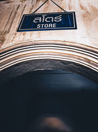 Low angle view of road sign against wall