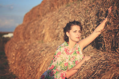 Young woman leaning on hay bale