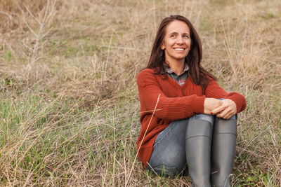 Portrait of a smiling young woman sitting on land