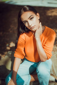 Young woman looking away while sitting outdoors