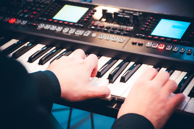 Cropped hands of man playing piano at home