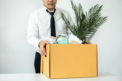 Midsection of doctor holding box against white background