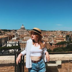 Young woman standing against buildings in city