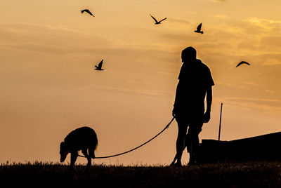 Silhouette man on field against sky during sunset