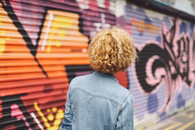 Young woman standing against graffiti shutter