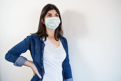 Portrait of young woman standing against white background