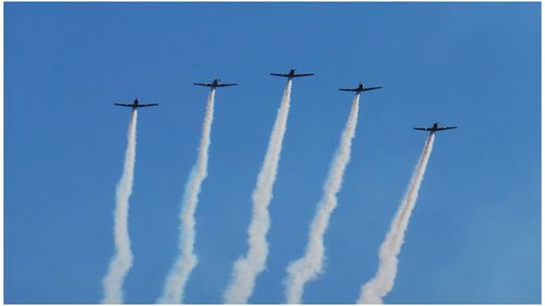 Low angle view of airplanes flying against sky