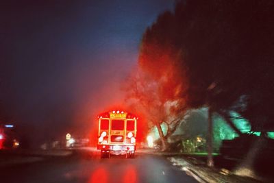 Illuminated road sign against sky at night