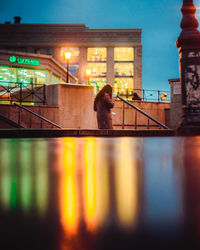 Full length of woman by illuminated city against sky at night
