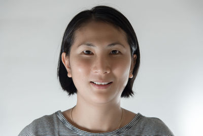 Portrait of smiling young woman against white background