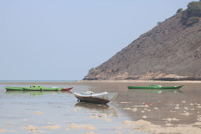 Boats moored on sea against clear sky